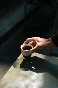 A person holding a cup of coffee on a table