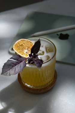 A drink with an orange slice and basil leaves
