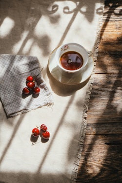 A cup of tea and cherries on a table