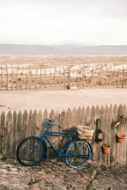 A blue bicycle leaning against a wooden fence