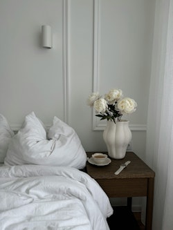 A white bed with a white pillow and flowers