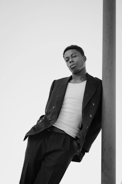 Man in Suit and Tank Top Leaning Against a Pole in Minimalist Setting - Black and White