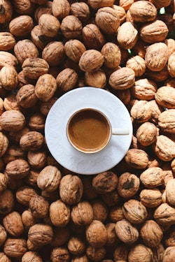 Coffee cup surrounded by walnuts