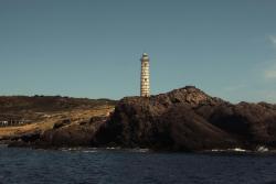 Beautiful lighthouse standing on rocky coast of Ustica Island, Sicily under a clear summer sky.