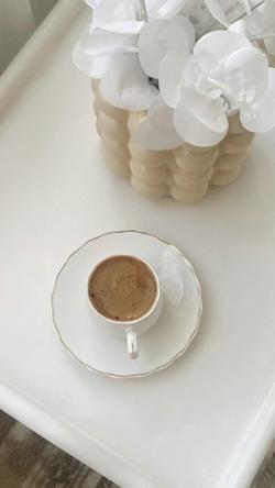 A minimalist scene with a coffee cup and decorative flowers on a chic white table.