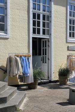 Clothing racks outside a boutique in Løkken, Denmark, under bright sunlight.
