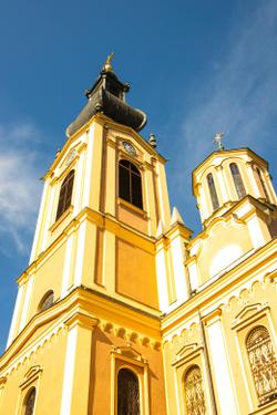 A bright yellow church with intricate architecture and a clear blue sky in Bosnia and Herzegovina.