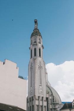 A vintage architectural tower captured under a cyan blue sky with clouds.