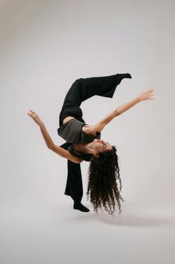 A modern dancer elegantly balancing with arms extended, showcasing flexibility and grace.