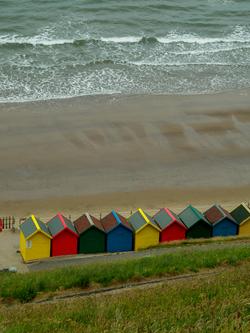 Aerial view of vibrant beach huts lining the Whitby shoreline, England.