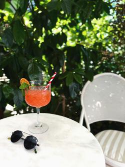 A vibrant cocktail with sunglasses on a sunlit patio, perfect for summer leisure.