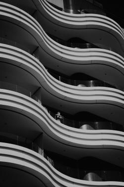 Black and white photo of a wave-like modern building facade with a person on a balcony.