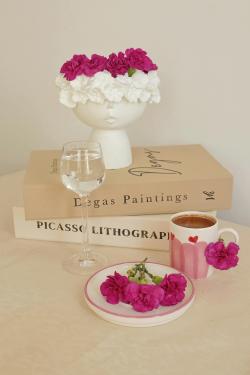 Artistic table with pink flowers, Degas and Picasso books, and coffee cup.