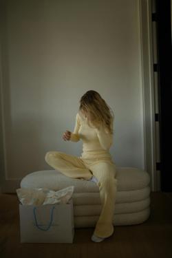 Woman in yellow loungewear sitting on cushions in a minimalist room.