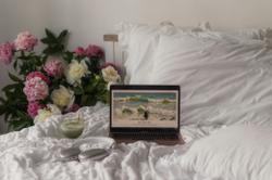 A lap  top is playing serene music next to a bouquet of peonies 