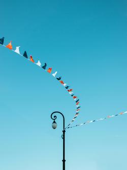 Colorful pennant flags curve gracefully against a clear blue sky, creating a vibrant visual.