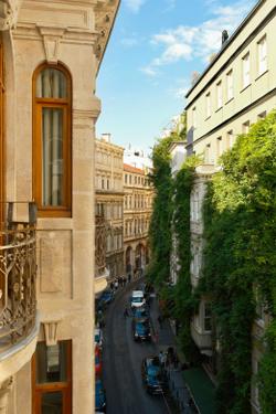 Scenic view of a European street lined with historic buildings and lush greenery.