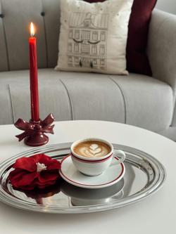 A warm and inviting coffee scene with a latte, red candle, and elegant decor in a cozy interior setting.